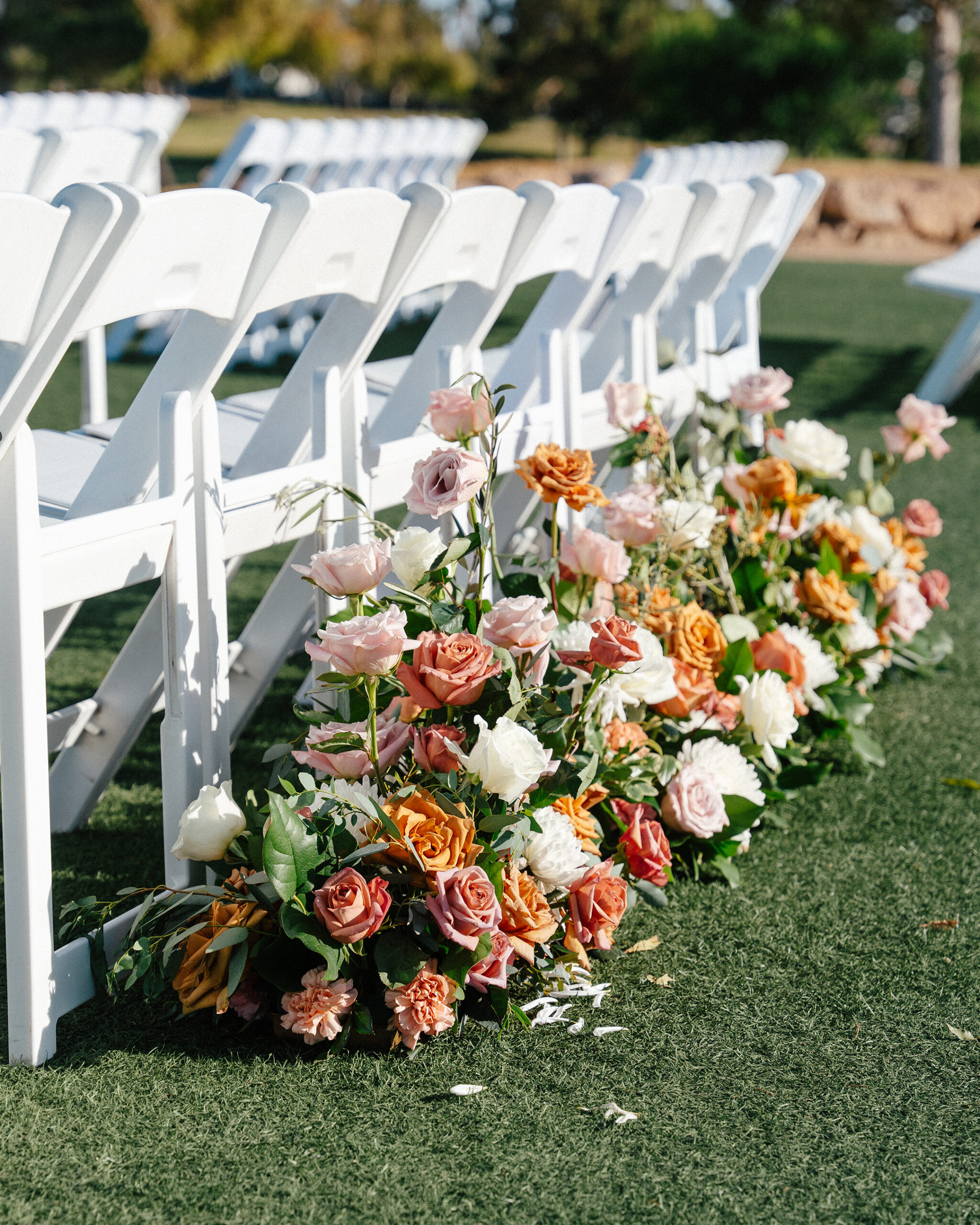 Rows of white chairs with floral aisle arrangements at a TPC Summerlin wedding ceremony in Las Vegas