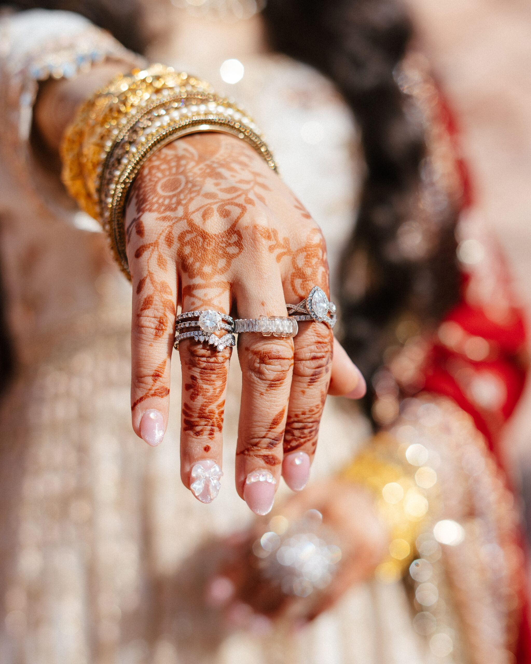 Close-up of bride’s henna-covered hand, rings, and gold bangles in red rock canyon wedding photo session