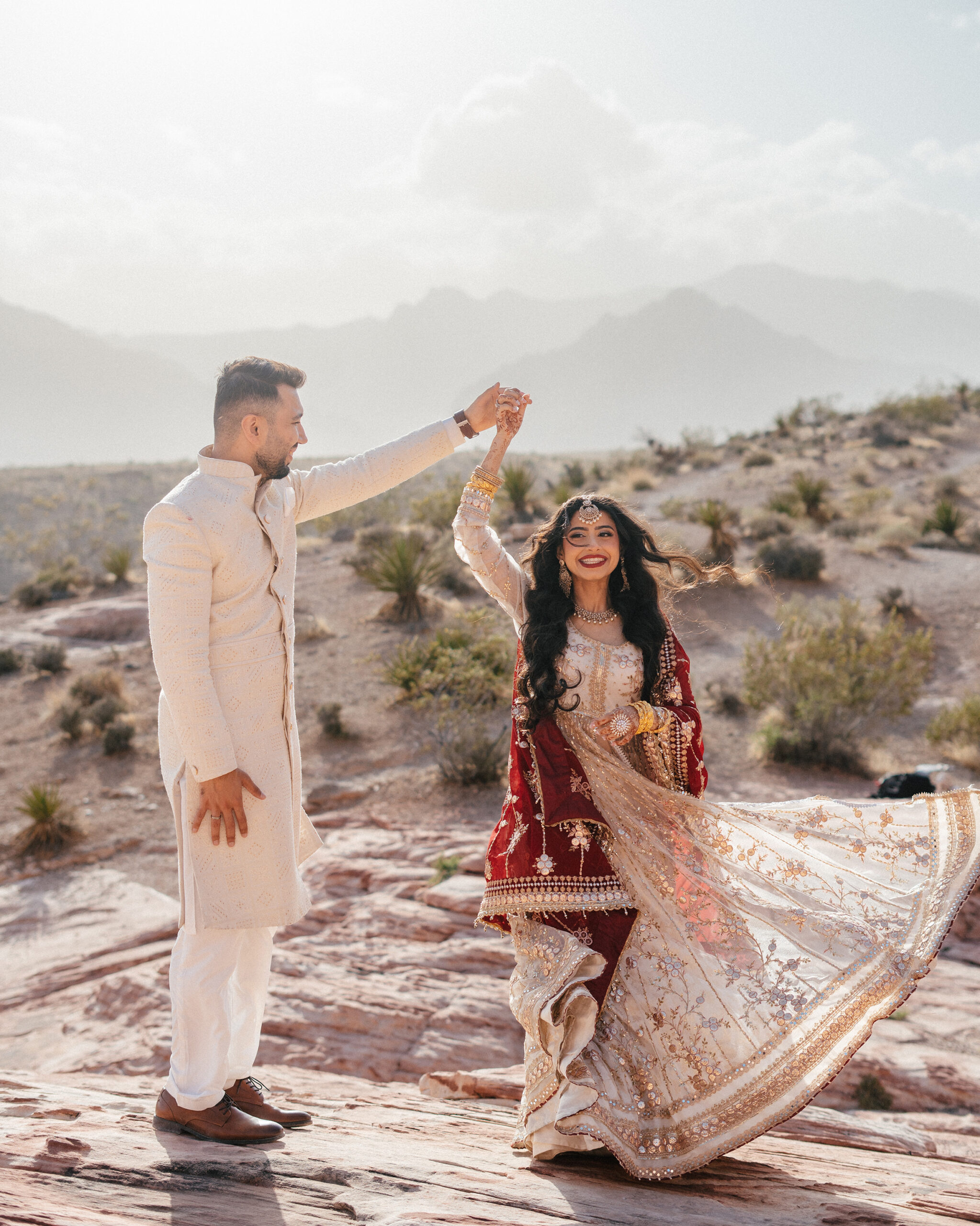 Bride spins with joy as her dress flows in the wind during red rock canyon wedding photos at golden hour