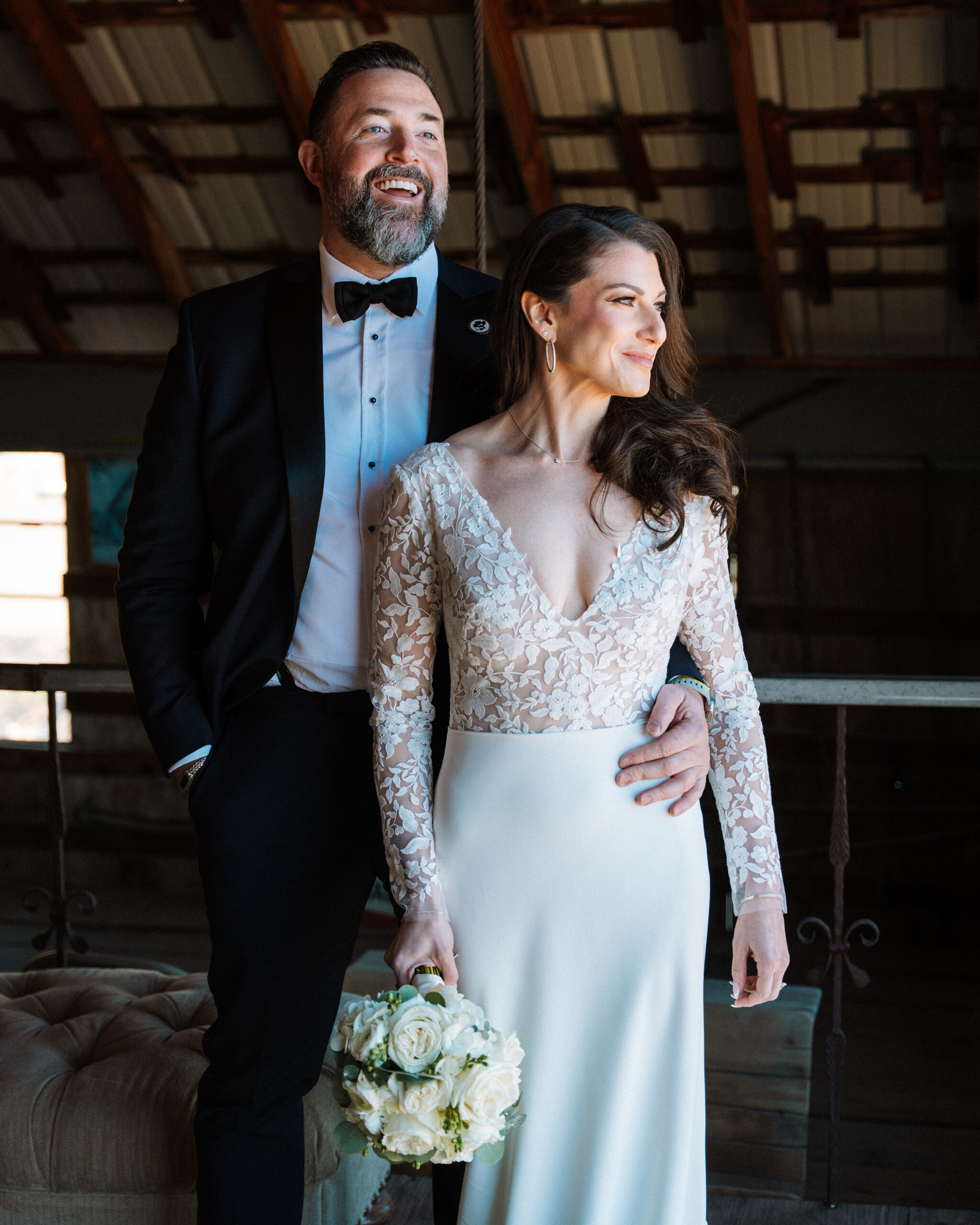 Bride smiling and standing next to ladder inside rustic barn at Nelson Ghost Town wedding