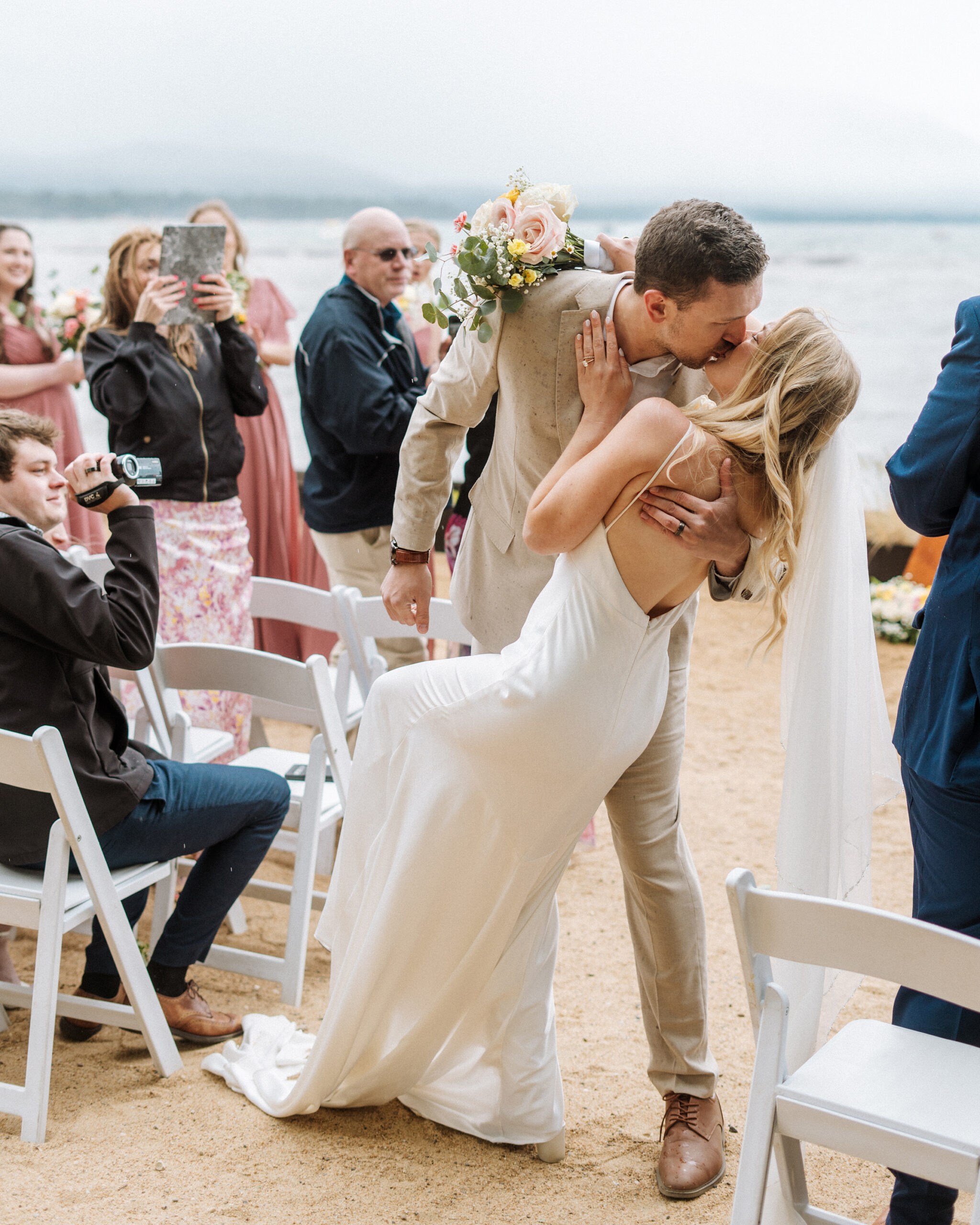 groom kisses his bride at wedding ceremony with beautiful views of lake tahoe in the background