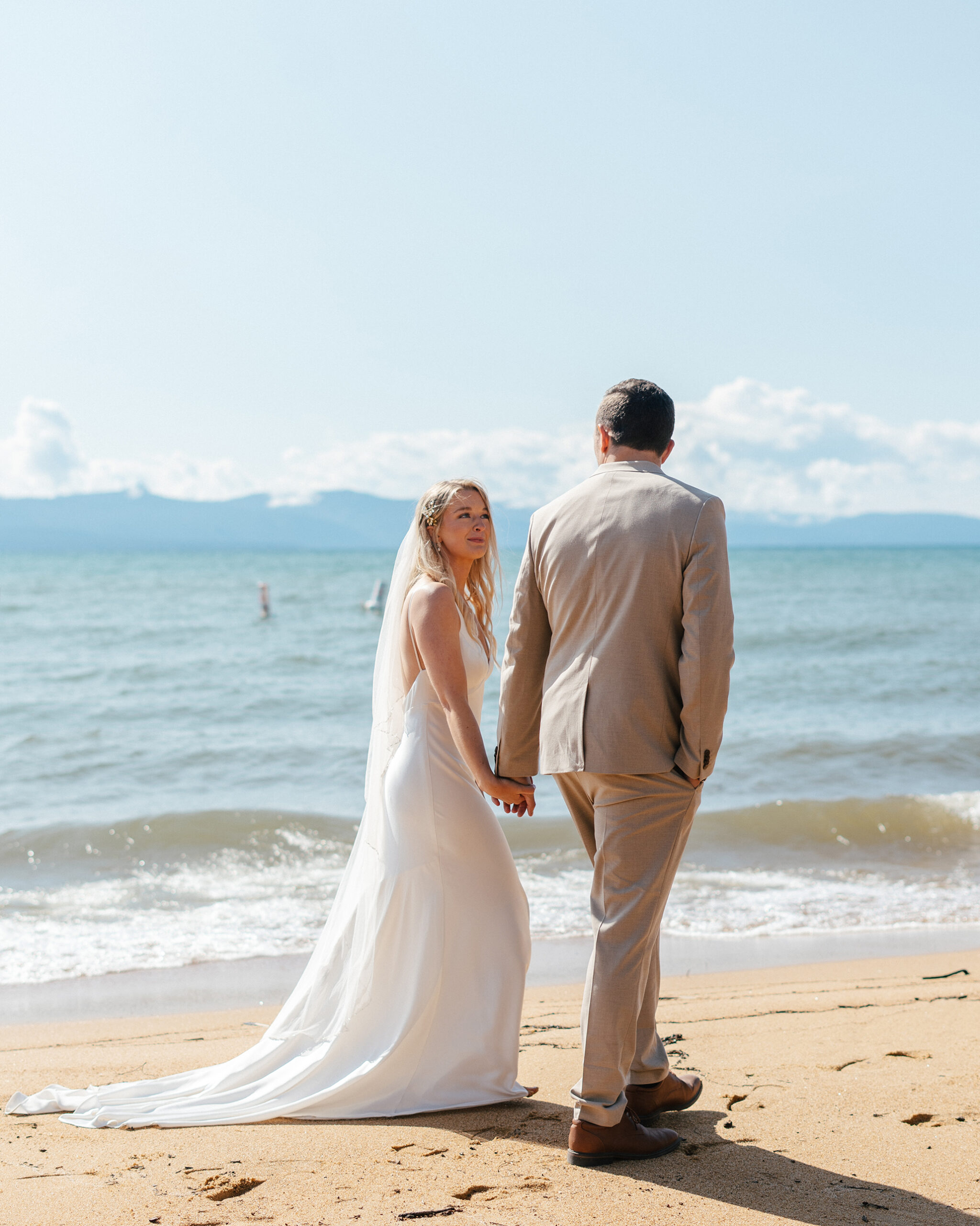 newlyweds walk down the beach after getting married at The Arch at Lakeside Beach