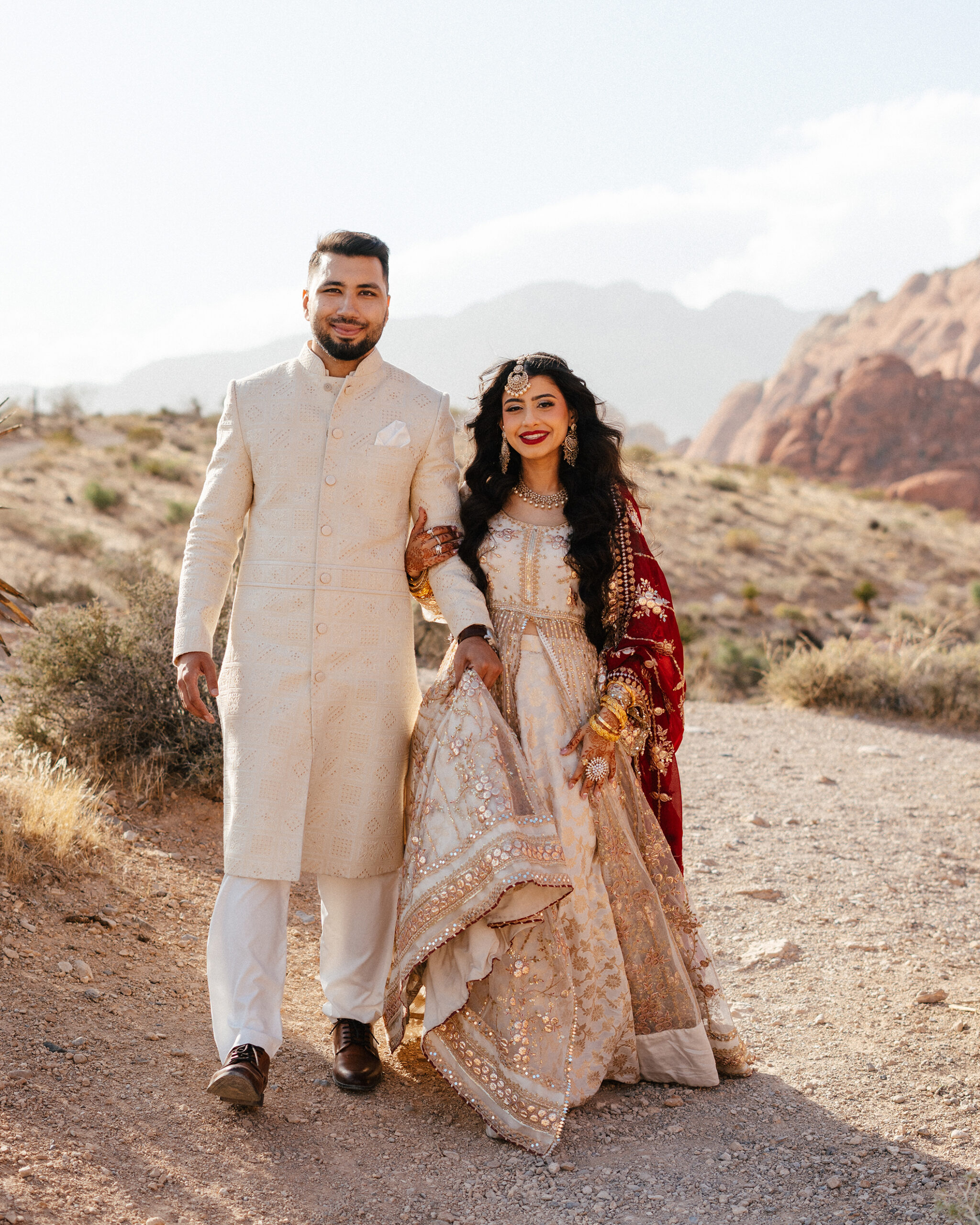 Bride and groom walk hand-in-hand across the desert floor during their red rock canyon wedding photo session