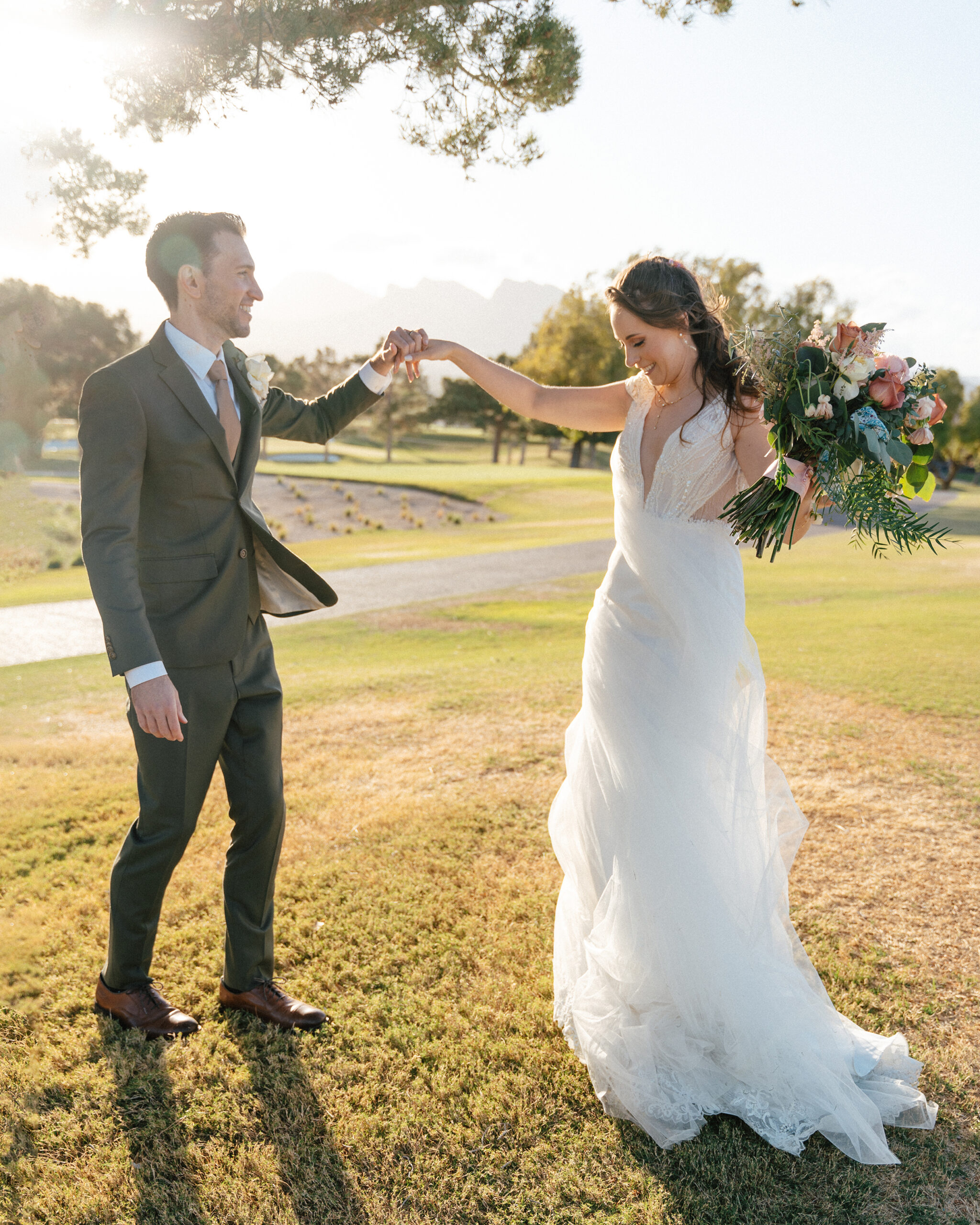 Bride twirls joyfully with groom on a grassy lawn with views of las vegas mountains in the background