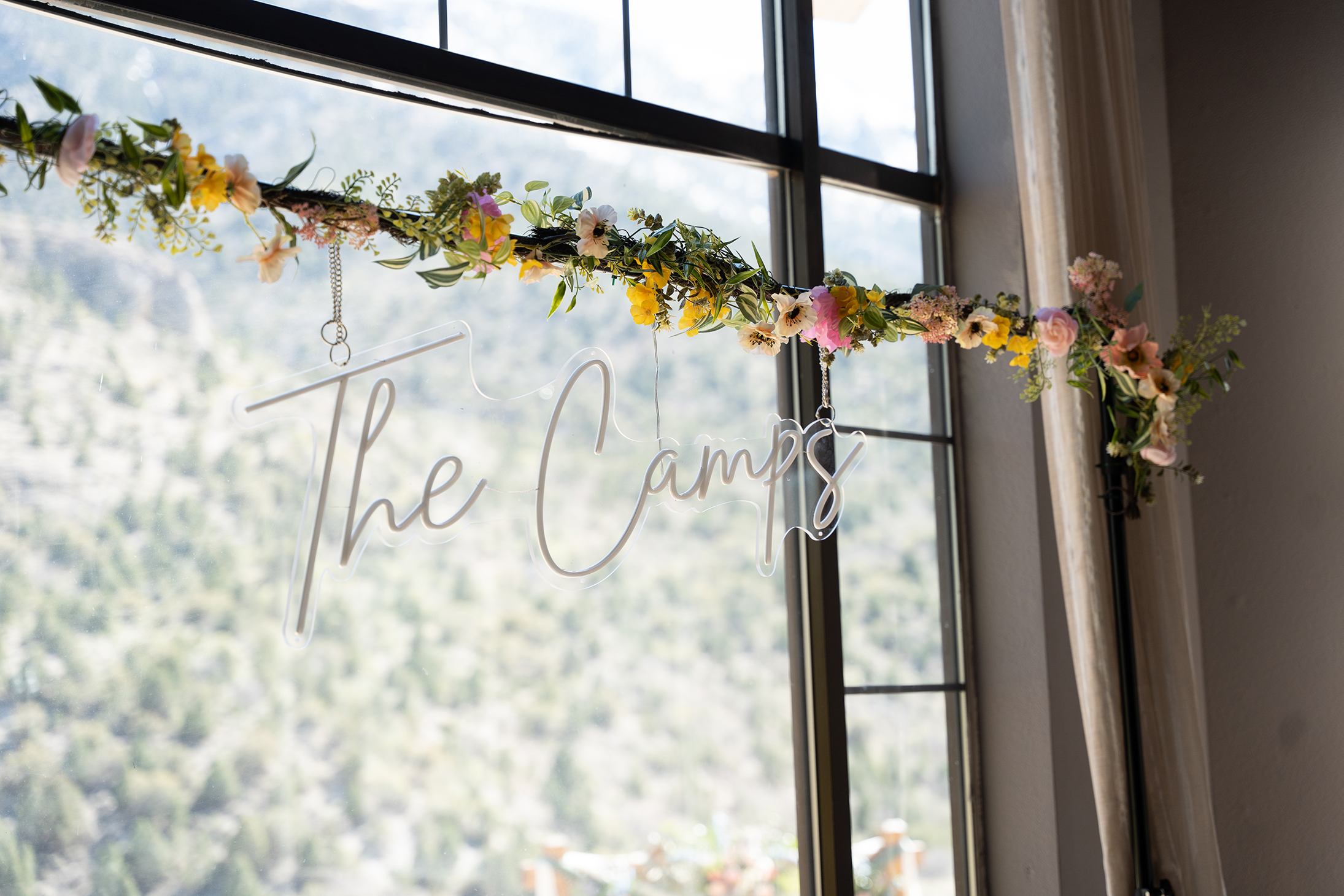 Hanging acrylic surname sign with floral garland in window at Mt. Charleston Retreat