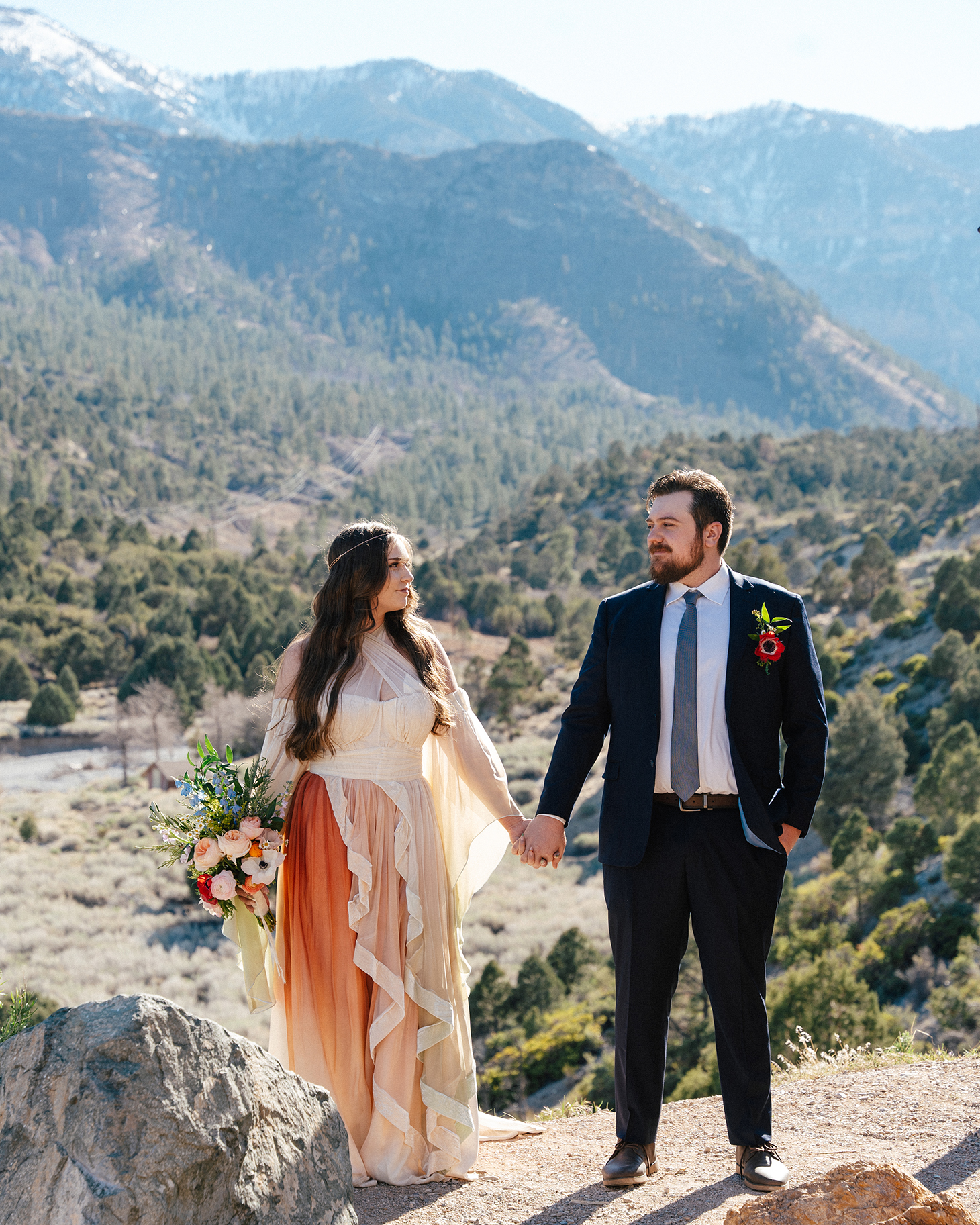 Bride and groom holding hands with snowy mountain views at Mt. Charleston Retreat