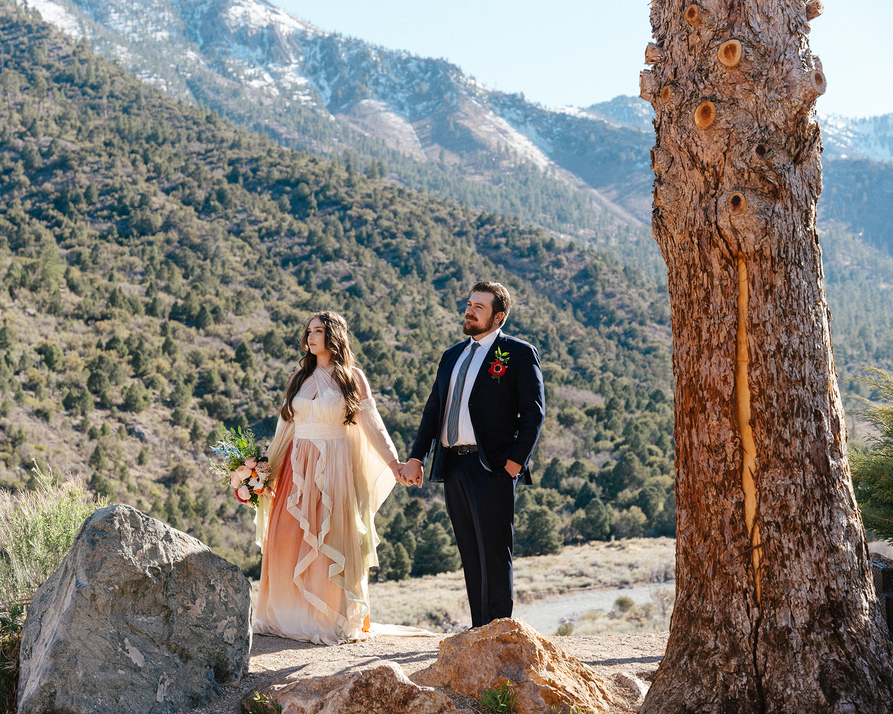 Bride and groom holding hands with snowy mountain views at Mt. Charleston Retreat