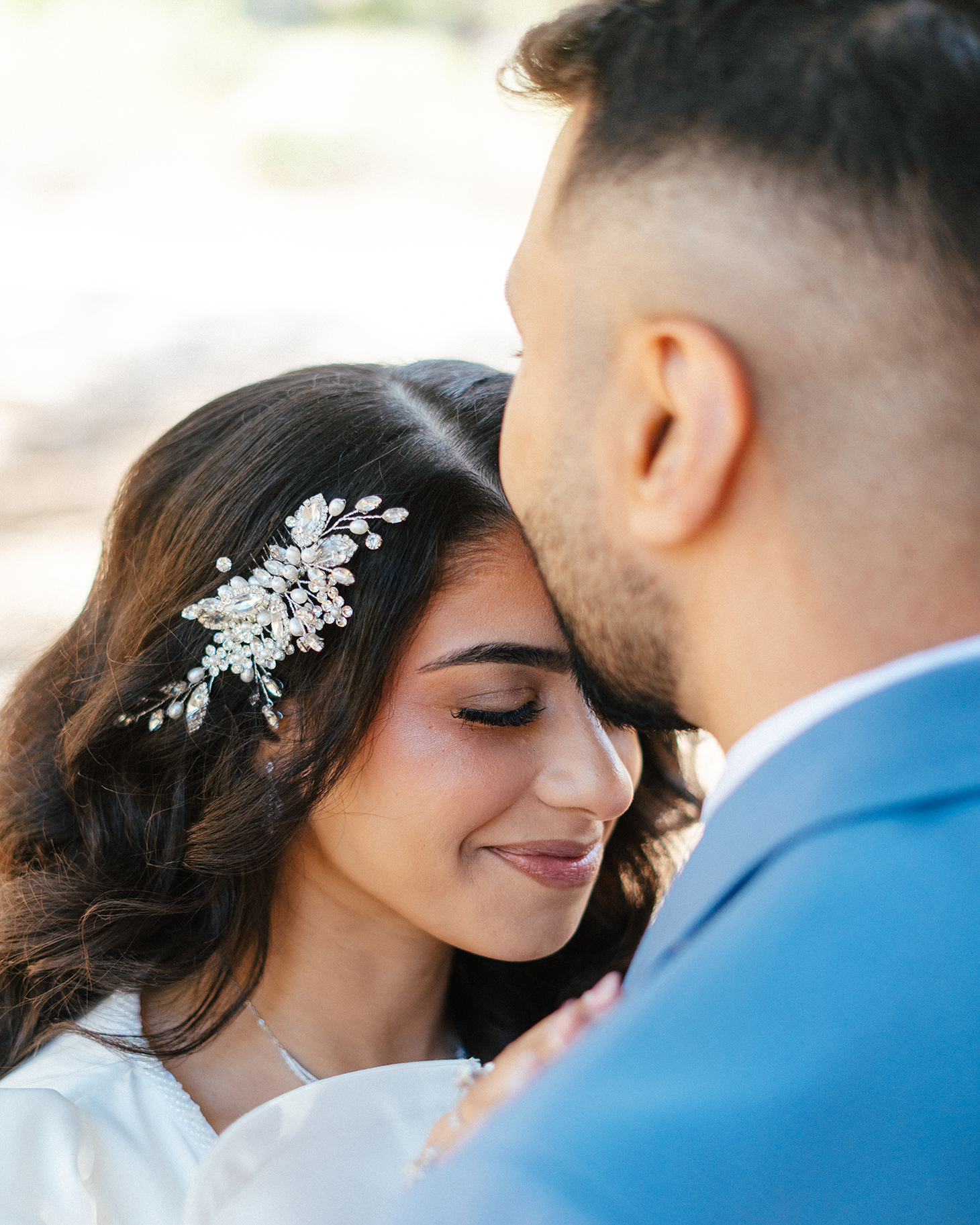 Bride smiles with eyes closed as groom kisses her forehead at Lee Canyon.