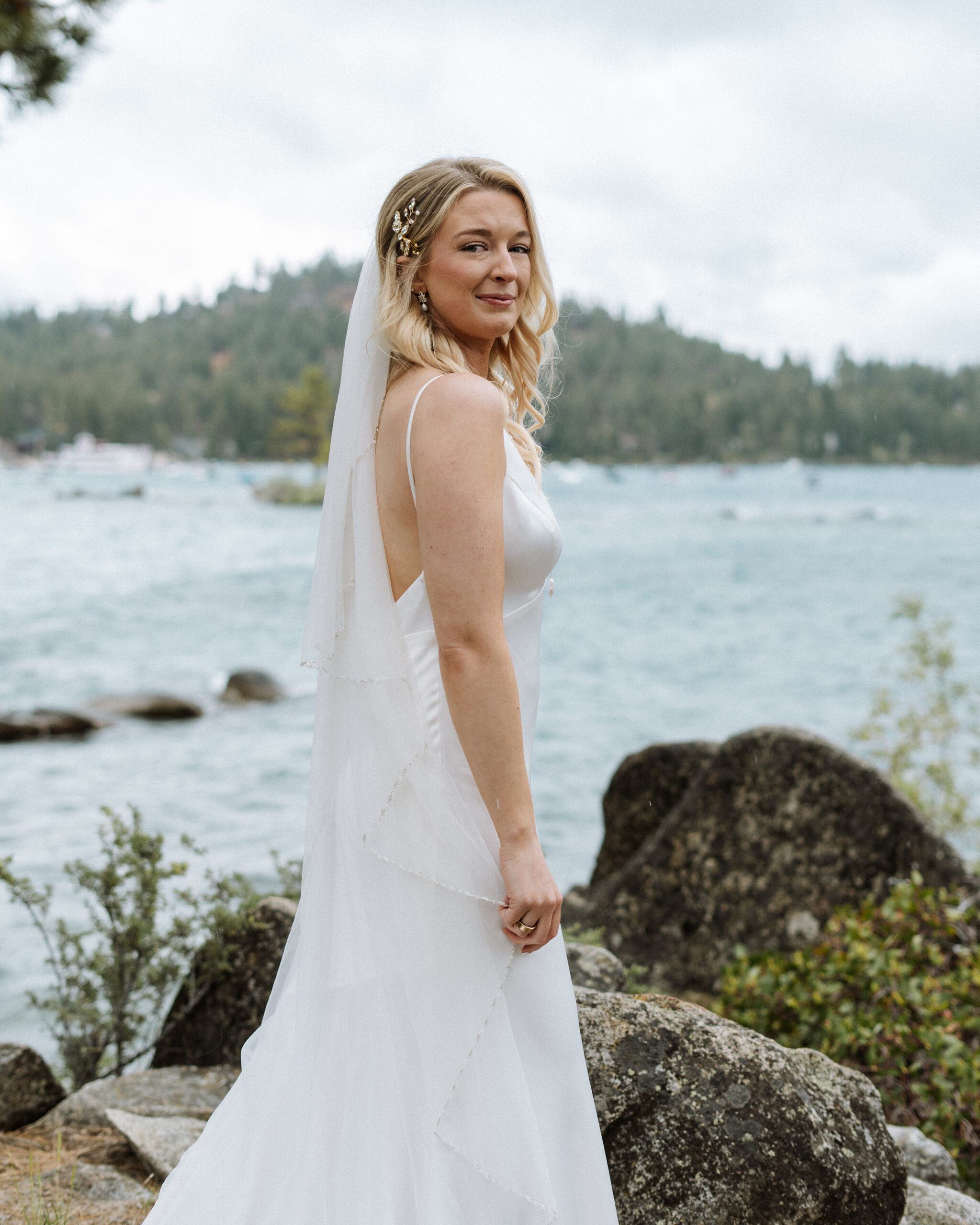 Elegant bridal portrait on the rocky shores of South Lake Tahoe, featuring a timeless white gown, soft veil, and natural lakeside beauty.