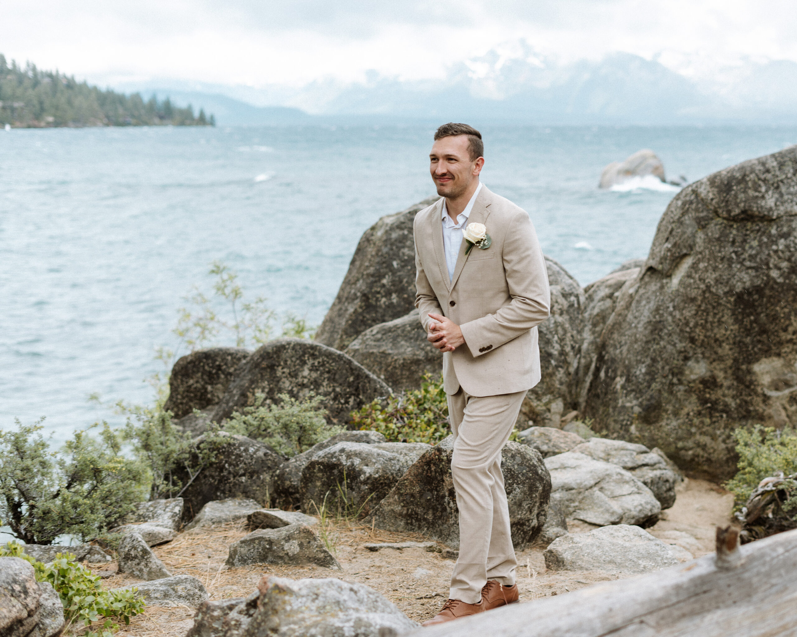 Classic groom portrait captured in South Lake Tahoe, featuring a neutral suit, soft florals, and the natural beauty of the lakeside mountain backdrop