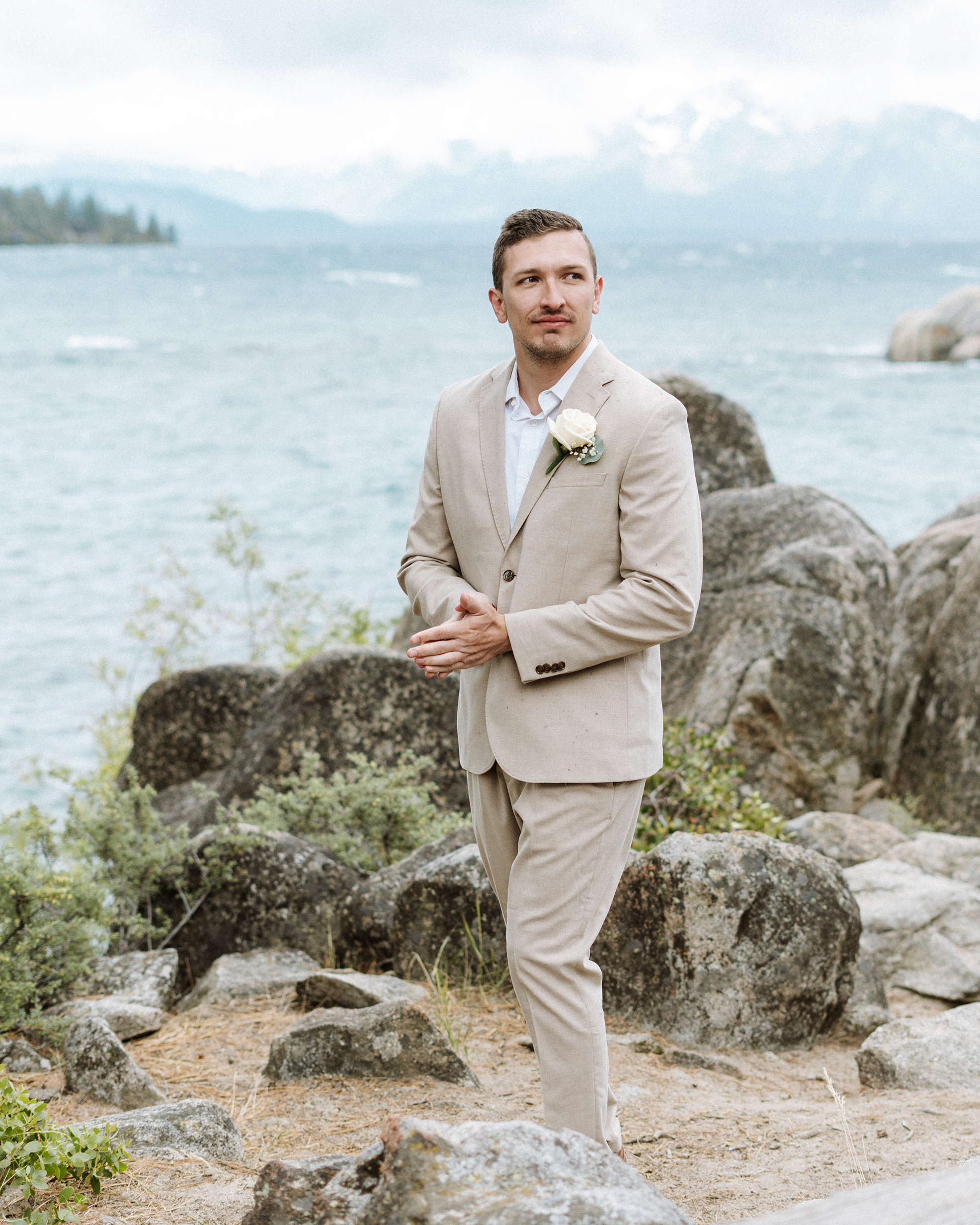 Classic groom portrait captured in South Lake Tahoe, featuring a neutral suit, soft florals, and the natural beauty of the lakeside mountain backdrop