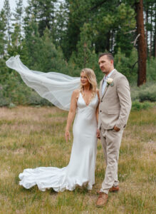 A joyful wedding moment in South Lake Tahoe as the bride and groom hold each other while her veil flows in the wind 