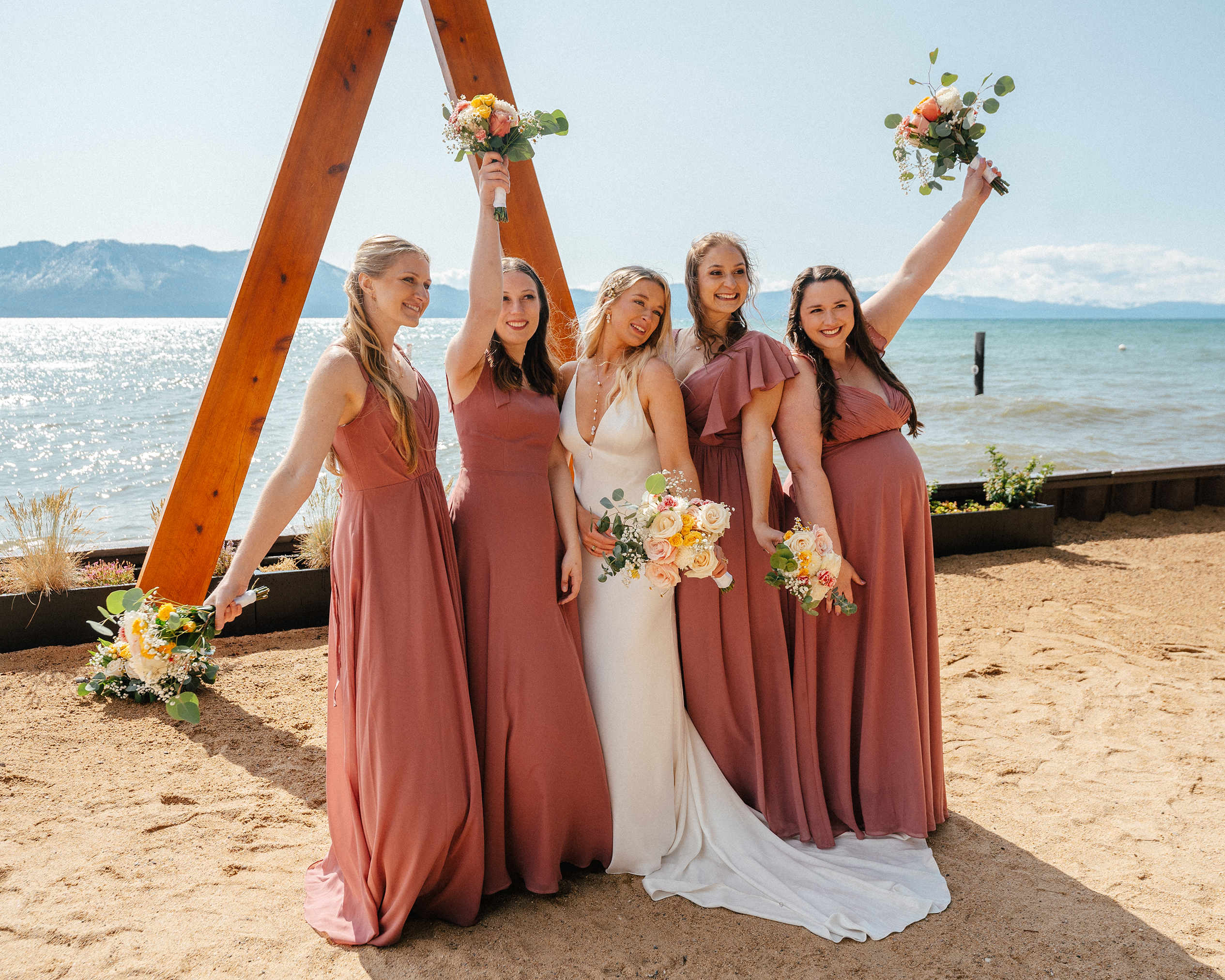  The bride and her bridesmaids pose with bouquets in hand after the ceremony at The Arch at Lakeside Beach in South Lake Tahoe.