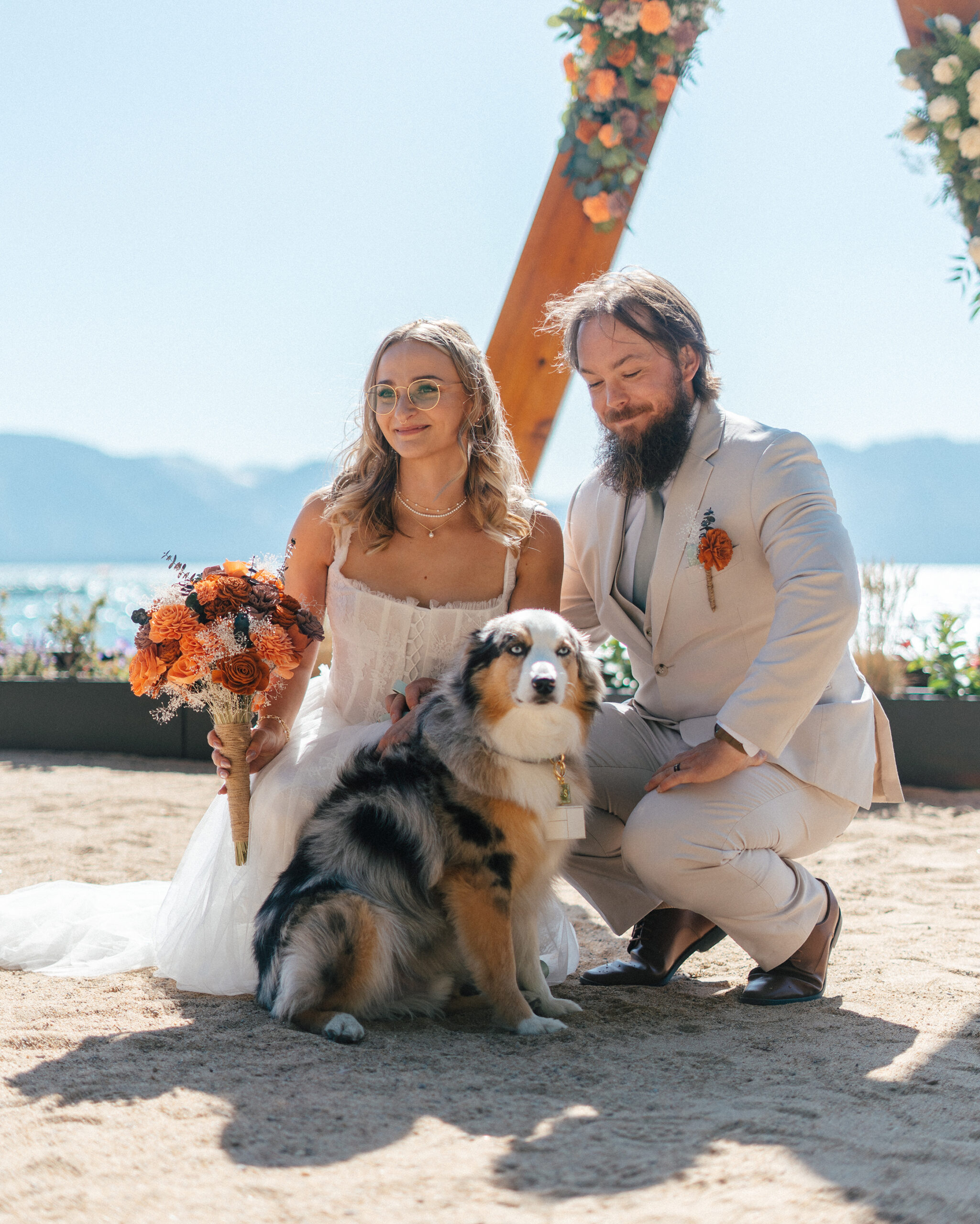 A joyful couple walks hand in hand with their dog after their Lake Tahoe beach ceremony.