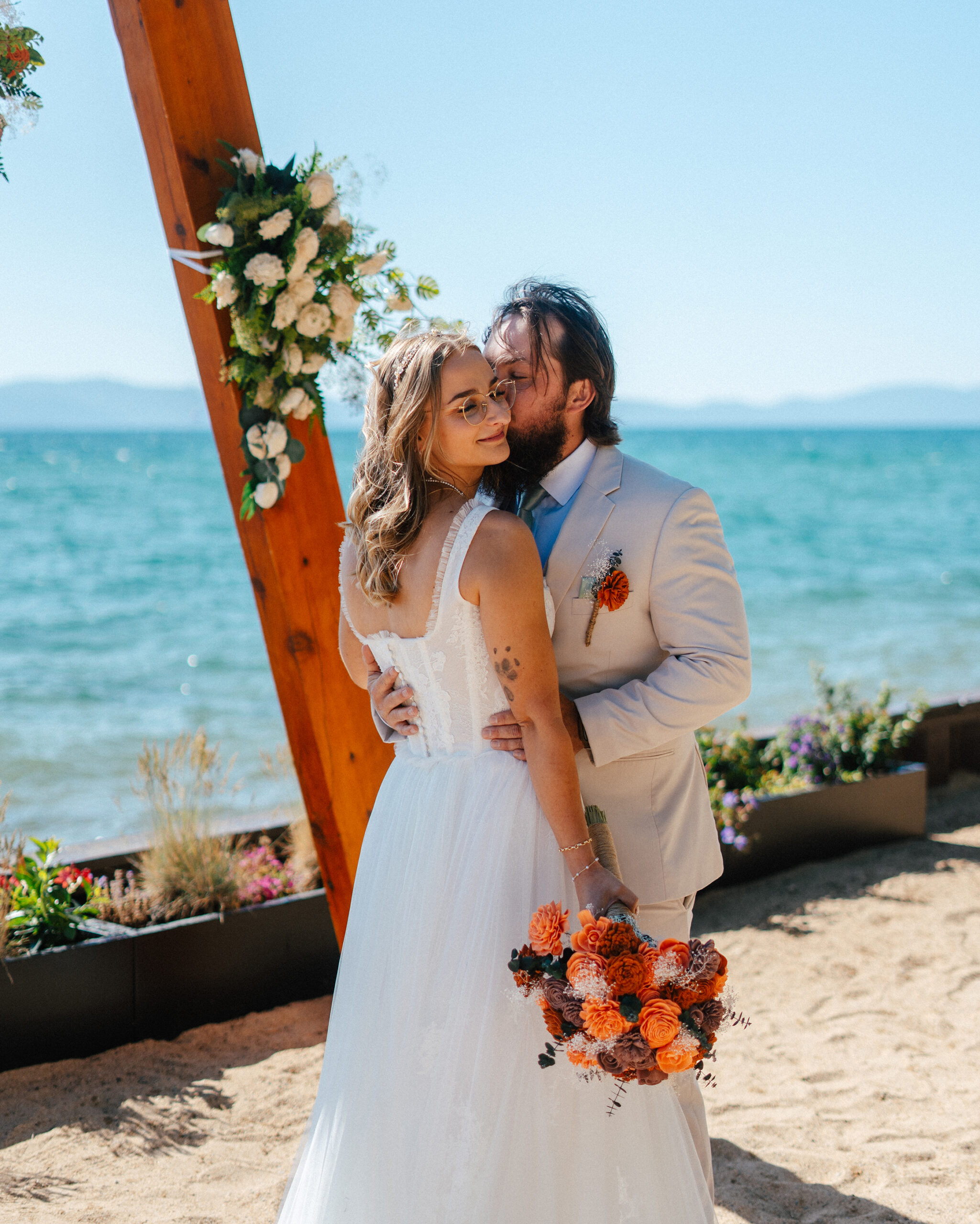 The groom kisses his bride in front of Lake Tahoe’s sparkling blue waters.