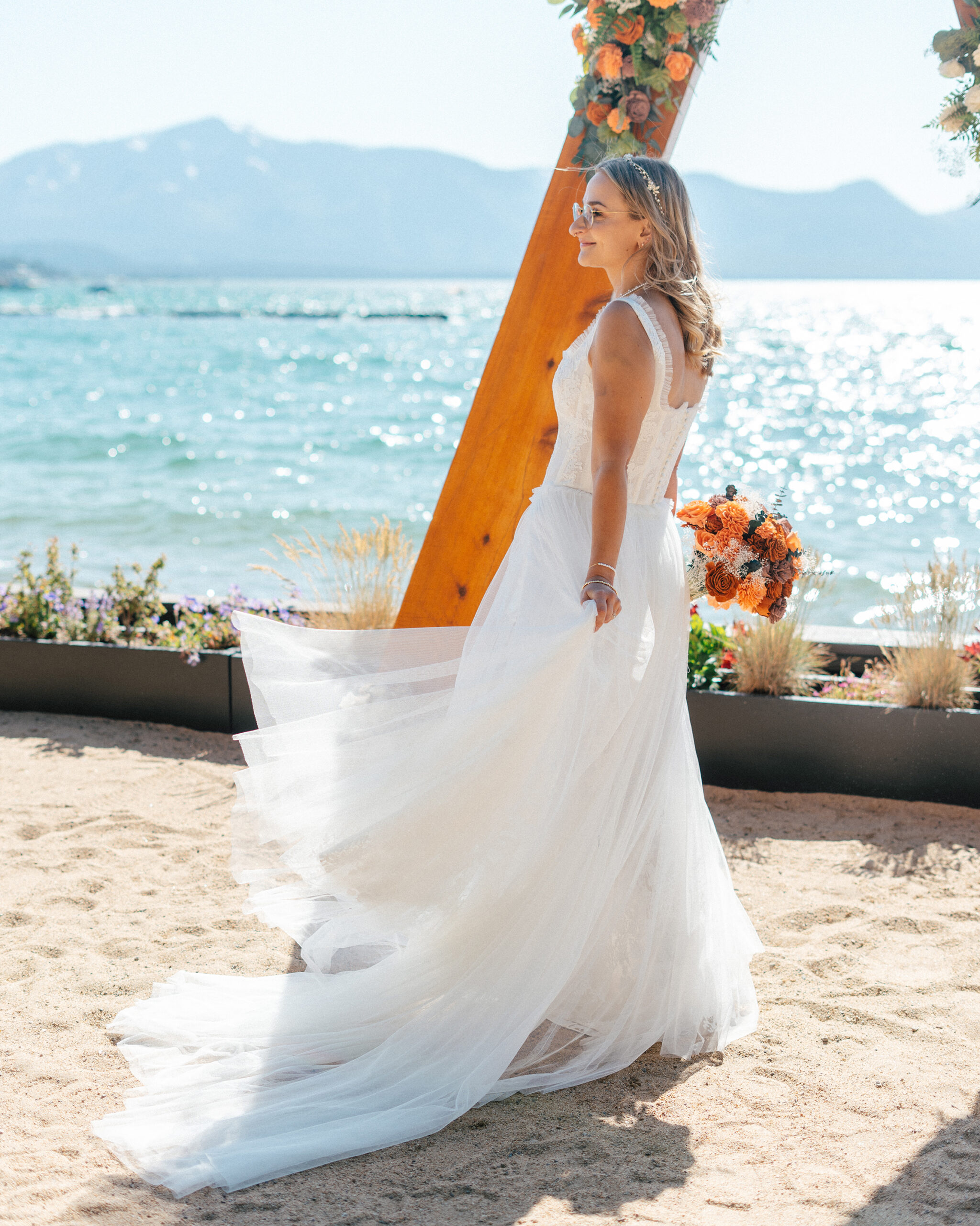 The bride twirls in front of the wooden arch, with Lake Tahoe sparkling in the background.