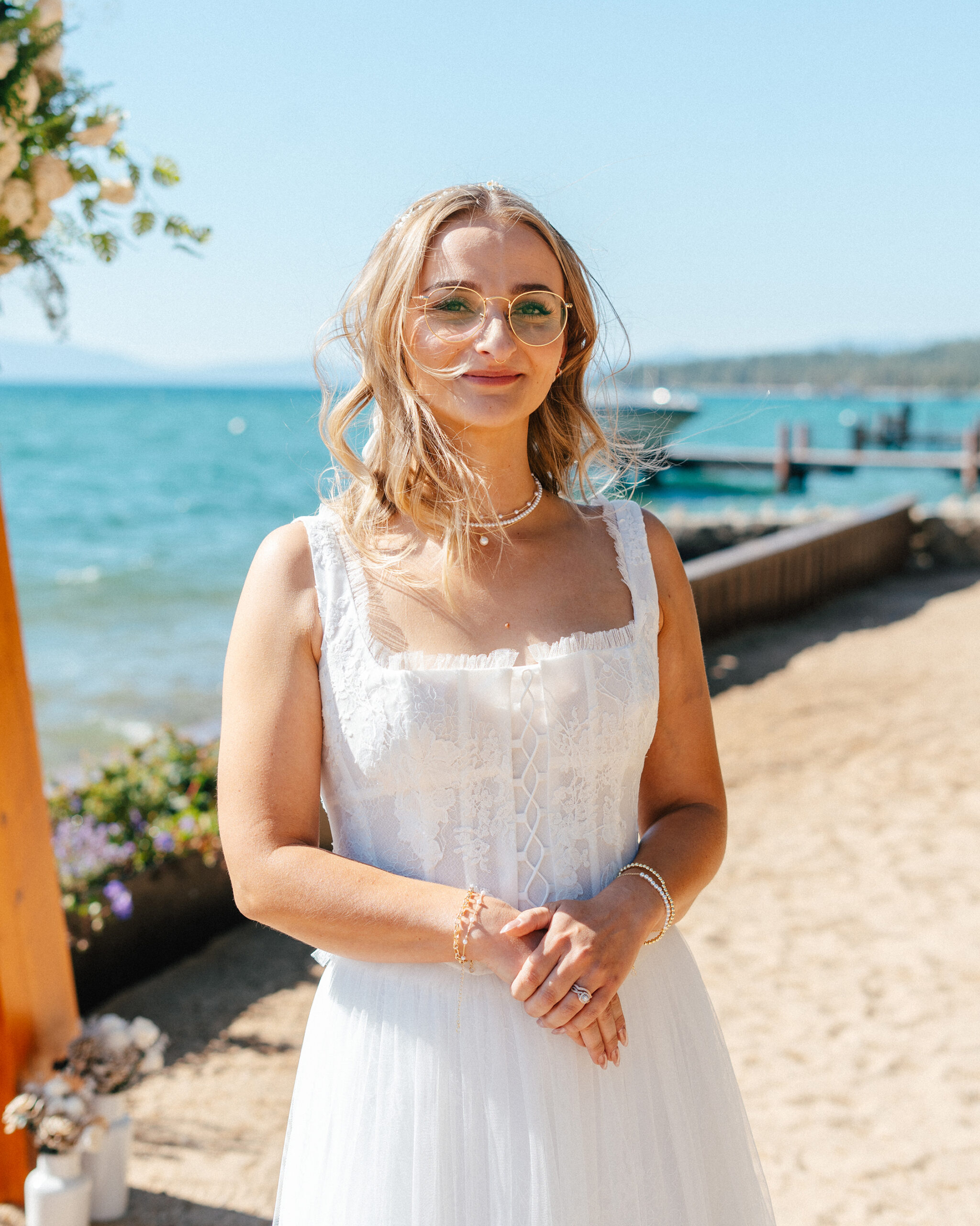 A happy bride stands by the water after her wedding at Lakeside Beach in South Lake Tahoe.