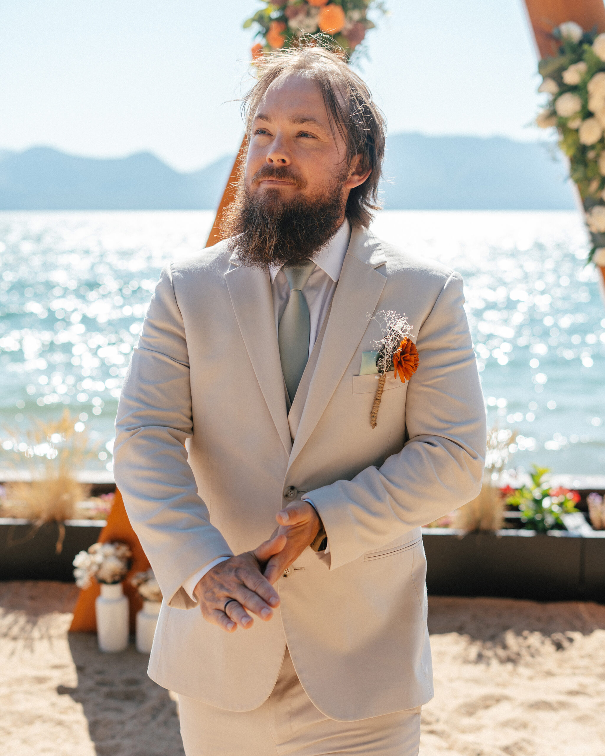The groom stands with a smile in front of the wedding arch at South Lake Tahoe.