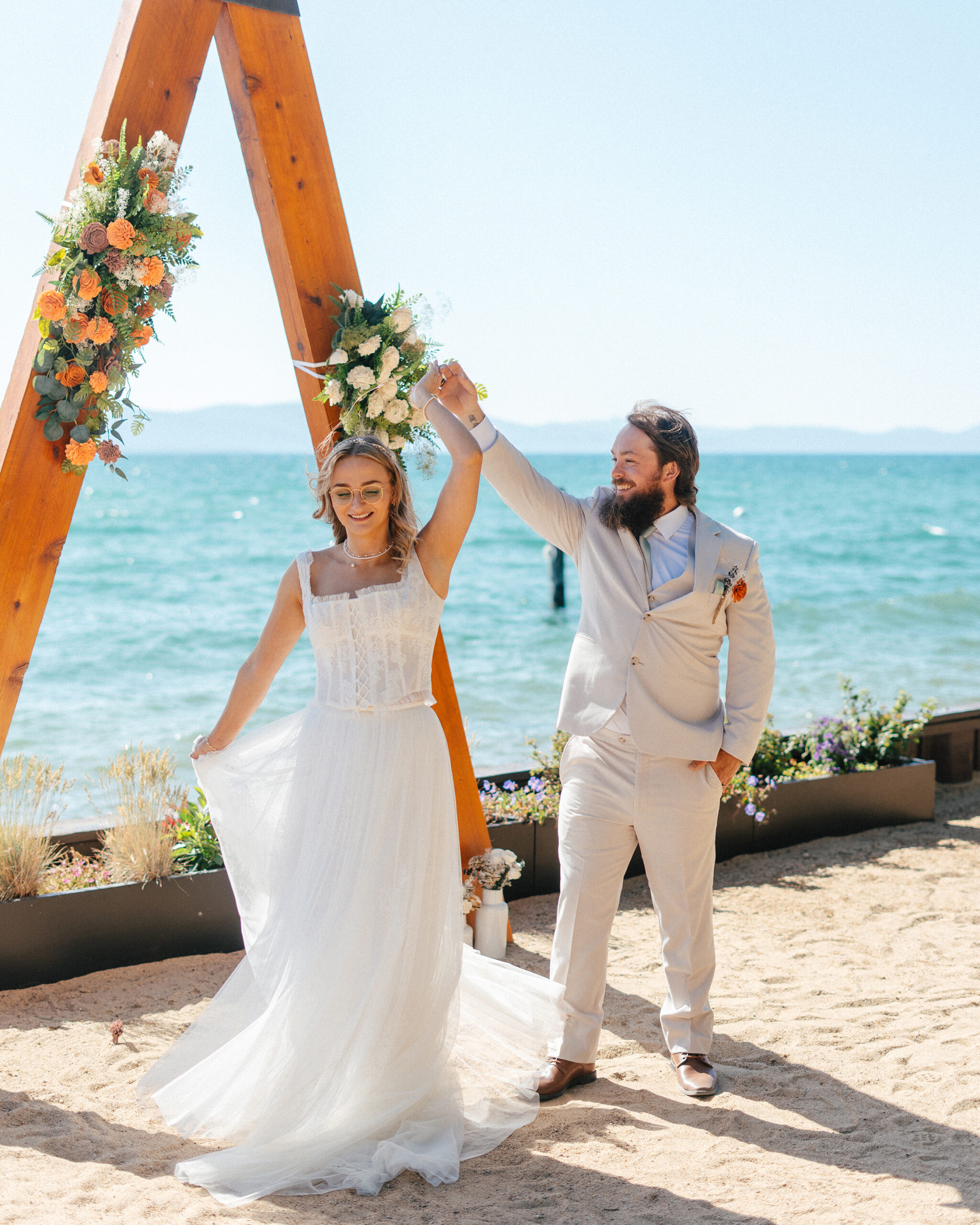 The bride dances beneath the arch at her sunny South Lake Tahoe wedding.