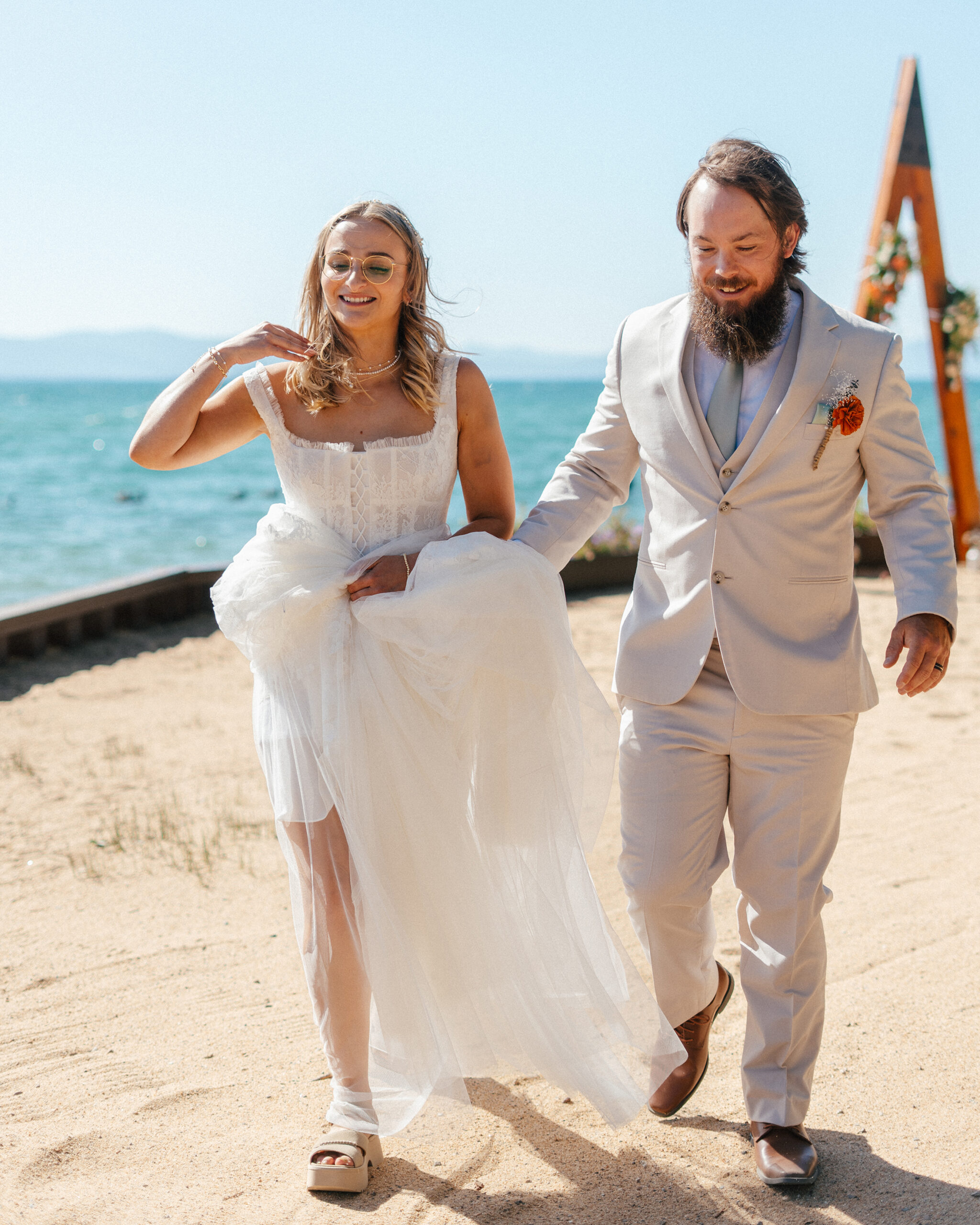 A candid moment of the bride walking barefoot along the sand.