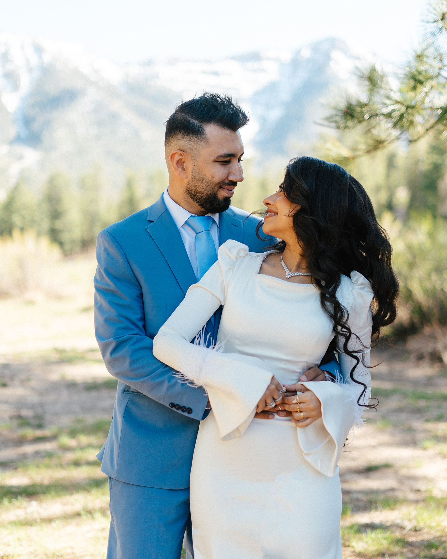 Smiling couple holding each other with Mt. Charleston’s snowy peaks in the background.