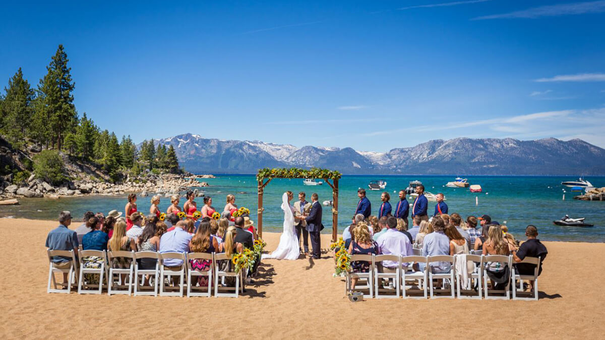 wedding ceremony takes place on a beach in lake tahoe on a beautiful sunny day